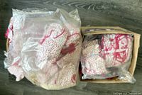 Photo of large plastic bags filled with doll clothes primarily featuring pink and white floral print tie tops.