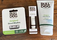 Original Face Wash 5.0 oz tube with aloe vera and Age Defense Eye Roll On tube 0.5 oz, alongside steel blade cartridges packaging.