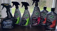Clear view of six product bottles on a table including Hope's Perfect Glass and Turtle Wax Hybrid Solutions