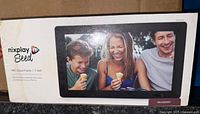 Box front showing product name, brand, and a photo of three people smiling and eating ice cream displayed on the digital frame screen.