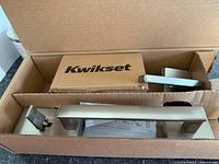 Fully assembled brushed metal handle in original Kwikset box with visible instructions.