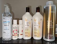 Front view of six beauty items including hand sanitizer and hair care bottles on a shelf.