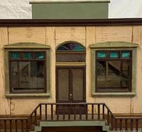 Front facade view showing double-door entry, flanking windows with stained glass panes and railing