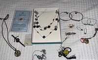 Photo showing assorted costume and sterling jewelry laid out on white textured fabric, including necklaces, bracelets, earrings, pins, a keychain, and sterling ring.