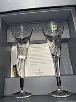 Two Waterford Crystal champagne flutes in original box with literature and labels intact.