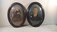 Two tall oval antique wooden frames with bubble glass and antique portrait photos of young males.