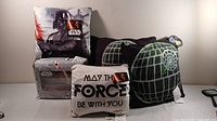 Four Star Wars themed throw pillows including Darth Vader, 'May The Force Be With You,' and two Death Star designs.