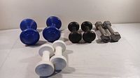 All four pairs of dumbbells displayed together with blue, black, white, and silver weights