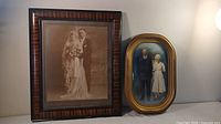Overall view of the two framed photographs showing the young wedding couple and the older couple side by side.