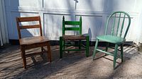 Three children's chairs: natural wood, bright green with wicker seat, and fully green painted with spindle back