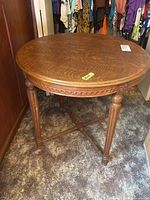 Full view of the round oak table showing carved legs and underside details.