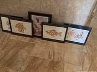 Five framed prints leaning against wall
