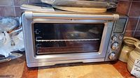 Front view of oven on countertop showing glass door, internal rack and Breville logo