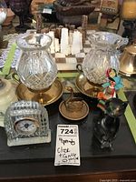 Overall view of the lot showing clock, candle holders, lighter, cat figurine, and folk art figurine