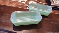 Two jadeite glass containers with lids displayed on table