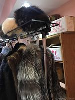 Silver fox fur hat on top shelf among other hats