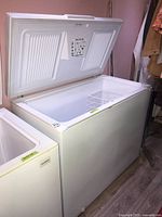 Closed white Kenmore chest freezer with the lid open showing interior and lock area.
