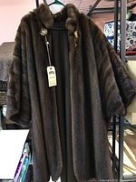 Full view of mahogany brown mink fur cape on hanger.