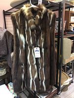 Front view of long ladies fur vest showing natural brown and white fur pattern and front pockets.