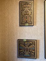 Wall display of two framed Indigenous-style prints, square bird motif above, rectangular humanoid motif below