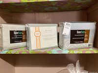 Three sheet sets on shelf: two HomeSuite wrinkle resistant sets and one Kimberley Seldon 400TC cotton set, all in original packaging.