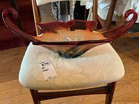 Side view of the multicolored art glass centerpiece on a fabric chair, showing its elongated red handles and rounded shape