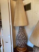 Full view of lamp showing ceramic base, wood plinth, and tall pleated shade