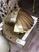 Globe-shaped pendant lamp seen from above, showing layered brass slats and hanging cord