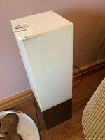 Full view of the lamp showing white rectangular shade made of heavy plastic on a dark base with cord visible on floor.