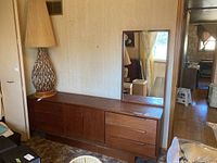 Full view of dresser with lamp beside and mirror leaning on top
