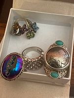 Four sterling silver rings displayed in a box showing all designs.