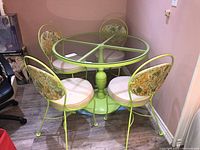 Overhead view of round glass-top table and four matching lime green metal chairs in basement setting