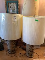 Full front view of two vintage ceramic base table lamps with pleated fabric shades, showing height and overall style.