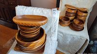 Stack of various wooden kitchenware items including large and smaller bowls, plates, and trays
