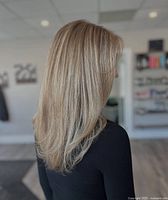 Photo showing a hairstyle with straight blonde hair with subtle highlights, representing salon hair coloring and styling.