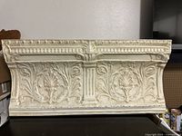 Front view showing embossed floral designs and cream paint with some aging and wear.