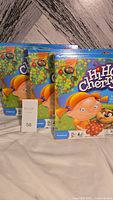 Three identical new sealed HiHo Cherry-O children's game boxes arranged side by side on fabric surface with lot number in front.