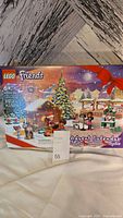Front view of the LEGO Friends Advent Calendar box showing the winter holiday scene with decorated Christmas tree, minifigures, reindeer, and gift boxes.