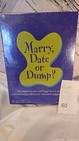 Front of new sealed Marry, Date or Dump? adult game box by Parker Brothers showing purple box with yellow butterfly design and title.