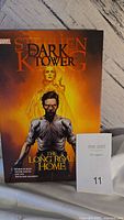 Front cover image of 'The Dark Tower: The Long Road Home' hardcover book showing characters and title.