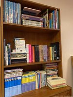 Photo of books on wooden bookshelf including boxed sets of The Hardy Boys and some fairy tale books on top shelf.