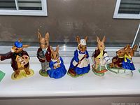Group photo of six Royal Doulton Bunnykins figurines on a windowsill, showing various characters and poses.