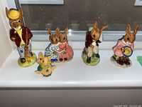 Five figurines displayed on a windowsill including four rabbits (Royal Doulton Bunnykins) and one mouse (Ganz Little Cheeser) figurine.