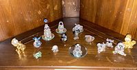 Wide photo showing all 13 crystal and glass figurines including animals, flowers, and a gold-tone human figure.