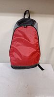 Closed red and black backpack shown from front
