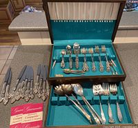 Full view of the entire set showing knives, flatware in velvet-lined box with ornate handles.
