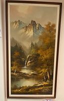 Full view of framed vertical painting with mountain landscape, waterfall, lake, and trees in autumn colors.