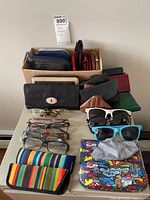 Eyeglasses, sunglasses, eyeglass chains, colorful cases and wallets arranged on a table