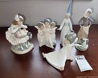 Five figurines displayed on table with a price tag visible