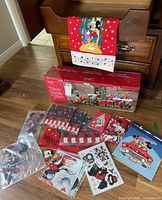 Overview of Mickey Mouse Christmas home goods including boxed holiday train, linens, stocking, and gift bags on wooden floor.